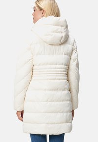 Witte pufferjas met een capuchon, voorzien van diagonale gestikte patronen, elastische aantrekking bij de taille en lange mouwen.