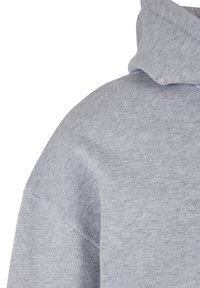 Felpa con cappuccio grigia con una texture morbida, vestibilità comoda e bordi grezzi sulle cuciture. Il tessuto appare leggero e traspirante.