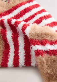 Punase ja valge triibuline kangas fluffika tekstuuriga, mille peale on lisatud pehmed beežikarva karvad, luues hubase välimuse.