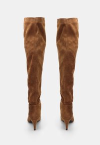 Bruna mockaskinn stövlar över knäet med en smal siluett, med en hög stilettklack och ren sömnad längs skaftet.