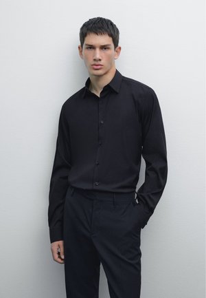 Black long-sleeve button-up shirt with a collar, plain fabric, slim fit, matching black trousers, smooth texture, simple design.