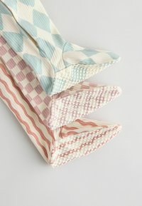 Három pár mintás kötött zokni pasztell színekben: világoskék gyémántmintás, rózsaszín hullámos, és krémfehér pöttyös. Strukturált mandzsetta.