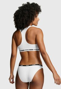 Weißer Sport-BH und passende Briefs mit einem schwarzen Puma-Logobund, im Racerback-Design und aus weichem Baumwollmaterial.