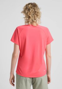 Korte mouw shirt in fel koraal, gemaakt van lichte stof. Heeft raglanmouwen en een fitted snit, met een subtiele logo aan de onderkant.