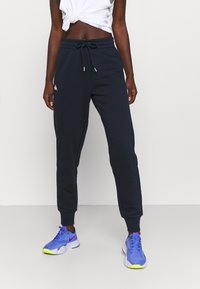 Navy sweatpants in soft fabric with an elastic waistband, adjustable drawstring, and ankle cuffs; features a logo detail on the side.