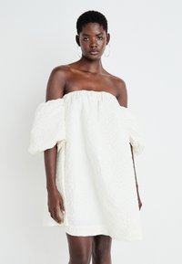 Biela off-shoulder šaty s vypchatými rukávmi, s textúrovanou tkaninou a voľnou siluetou A-líne, poskytujúcou uvoľnený strih.