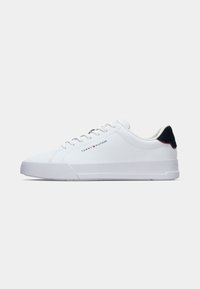 Baskets basses blanches avec lacets, languette de talon noire et logo Tommy Hilfiger sur le côté.