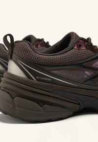 Brune mesh-sneakers med kontrasterende mørke accenter, en tekstureret mellemsåle, reflekterende detaljer og en trækflap ved hælen for nem påtagning.