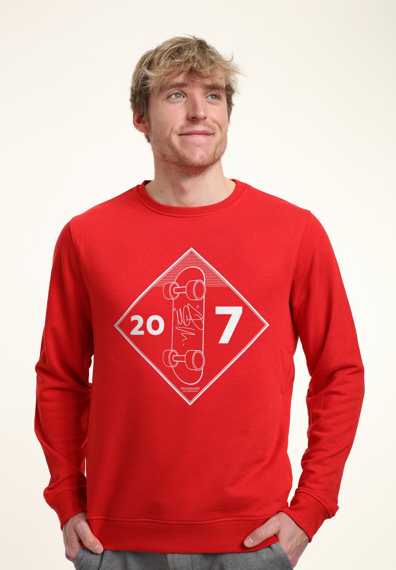 Felpa rossa con maniche lunghe, caratterizzata da un motivo grafico bianco di uno skateboard e dai numeri "20" e "7" all'interno di una forma a diamante.