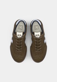 Baskets en daim marron avec des accents blancs, bout rond et design à lacets. Tige texturée et semelle en caoutchouc avec un détail cousu. Logo de la marque visible.
