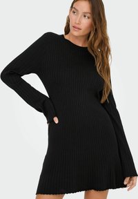 Robe noire en tricot côtelé avec des manches longues, un encolure ronde et un ourlet évasé. Texture douce avec un design ajusté.