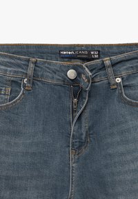 Slim-Fit-Denim-Jeans in dunkelblauer Waschung mit sichtbaren Nähten und Frontreißverschluss. Mit Markenlabel, das am Bund angenäht ist. Größe W32 L32.