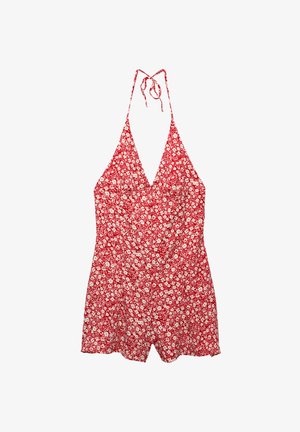 Crveni cvjetni kombinezon s halter vratom, prilagođenim trupom, lepršavim kratkim hlačama i vezicama. Sadrži male bijele cvjetne uzorke na teksturiranom materijalu.