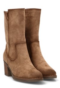 Botas de tobillo de ante marrón con punta ligeramente afilada, paneles laterales elásticos y un tacón bajo y apilado. Textura suave con detalles de costura.