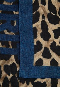 Leopardmønsterstof i beige og sort, kantet med en mørkeblå tekstureret trim med synlige sømme. Har fed skrift i samme blå farve.