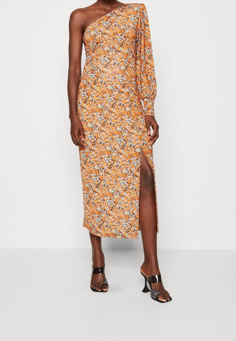 Én-skulder midi kjole i orange med blomsterprint, der har en lang ærme, sideslids og let stof. Sæt sammen med sorte open-toe hæle.