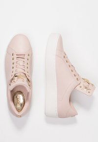 Sneakers in pelle rosa con dettagli a stella, accessori in oro, suola piatta bianca e punta rotonda. Presentano un laccio anteriore e un colletto imbottito.