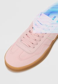 Ljusrosa sneakers med övre i canvas, gummisul och texturerade skosnören. Har logotyp på sidan och stickade detaljer längs designen.
