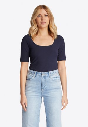 Donkerblauw geribbeld topje met een ronde hals en korte mouwen, gedragen met lichtblauwe high-waisted jeans. Zachte textuur, aansluitend ontwerp.