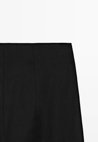 Zwarte high-waist rok met een rechte snit en zichtbare verticale naaddetails op een eenvoudige lichte achtergrond.