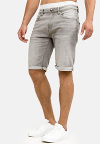 Lichtgrijze denimshorts met een omgerolde zoom, voorzien van een knoop- en ritssluiting, riemlussen en subtiele whisker-details.