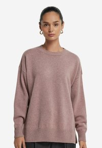 Rosa Strickpullover mit rundem Halsausschnitt, überschnittenen Schultern und gerippten Bündchen und Saum. Weiche Textur und lockere Passform, geeignet für die Freizeit.