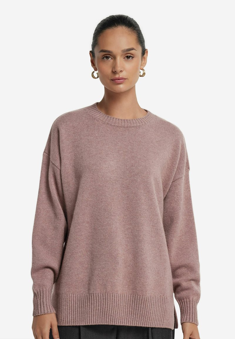 Rosa Strickpullover mit rundem Halsausschnitt, überschnittenen Schultern und gerippten Bündchen und Saum. Weiche Textur und lockere Passform, geeignet für die Freizeit.