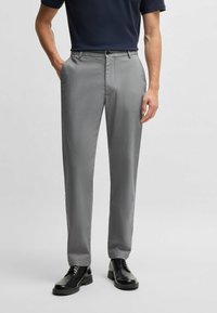 Gray patterned trousers made from textured fabric. Features a button closure and side pockets, paired with polished black shoes.