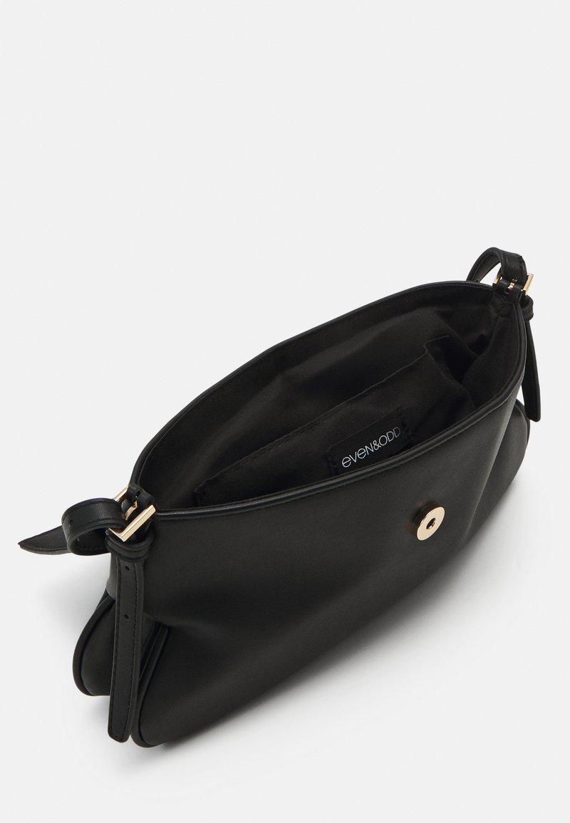 Borsa a tracolla in pelle nera con una texture liscia, chiusura con zip, accessori in oro e un ampio interno con un'etichetta di marca.