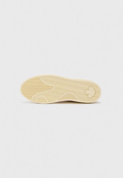 Skosula i beige gummi med fiskbensmönster, med rund tå och subtil varumärkesdetalj.