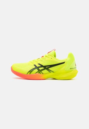 Scarpa da atletica neon gialla con accenti neri, rete traspirante, suola con grip testurizzato e una sfumatura rosa-arancio sulla suola.