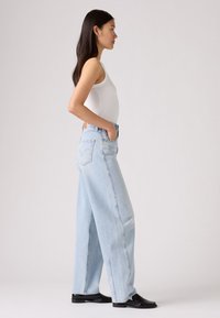 Jeans a vita alta di colore azzurro chiaro, con gamba ampia e silhouette dritta, dotati di cinque tasche e un'etichetta in pelle con logo sul retro.