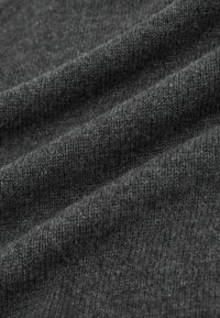 Donkergrijze gebreide stof met een zachte textuur, zichtbaar met patronen van verweven draden en zachte golven door de val van de stof.