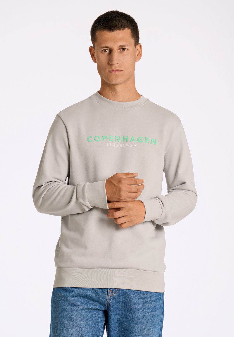 Sudadera gris con cuello redondo y mangas largas. Presenta "COPENHAGUE" en impresión verde en el pecho. Ajuste casual, puños y dobladillo acanalados.