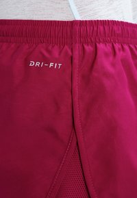 Červené šortky Dri-FIT s texturovaným povrchem, elastickým pasem a síťovanými bočními panely pro ventilaci. Logo zobrazené v bílé barvě.