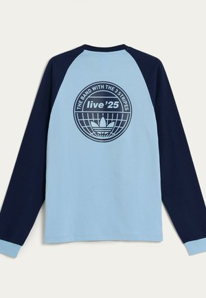 Langsleeve shirt met een lichtblauwe body en marineblauwe raglanmouwen. Heeft een cirkelvormig grafisch logo op de achterkant met tekst en een centraal motief.
