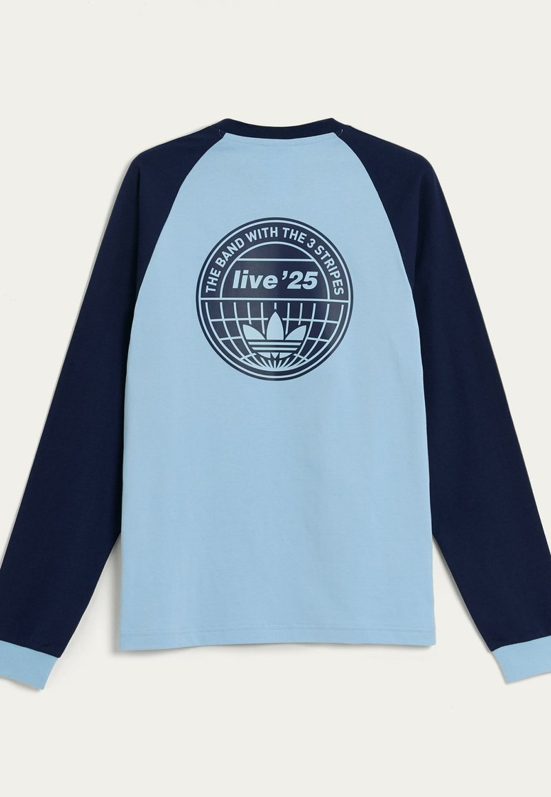 Maglietta a maniche lunghe con corpo azzurro chiaro e maniche raglan blu navy. Presenta un logo grafico circolare sul retro con testo e un motivo centrale.