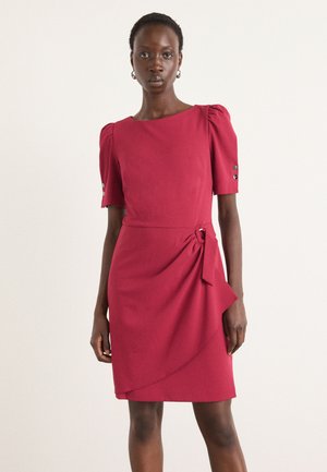 Himbeerrotes Kleid aus glattem Stoff, mit kurzen Puffärmeln, einer Knotenapplikation an der Taille und einem überliegenden Stoff, der seitlich herabfällt.