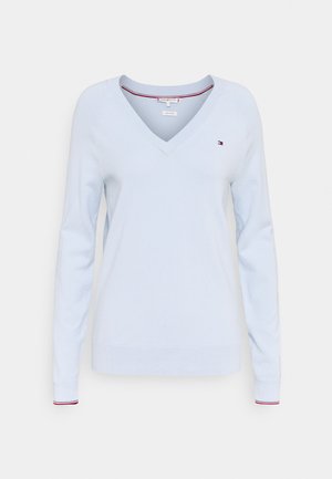 Lichtblauwe V-hals trui met lange mouwen, met een klein rood, wit en blauw logo op de linkerborst en geruite manchetten.