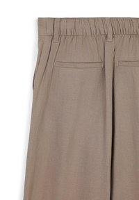 Pantaloni in tessuto intrecciato color sabbia con vita elastica, dotati di due tasche posteriori e una vestibilità rilassata, offrono una texture morbida e un design pratico.