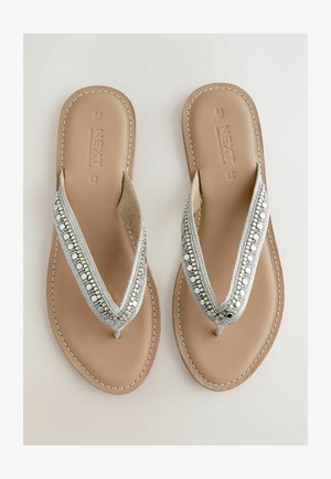 Srebrne sandały na płaskiej podeszwie z koralikowym paskiem, z beżową, gładką podeszwą i teksturowaną wkładką. Detale przeszyć wzdłuż krawędzi.