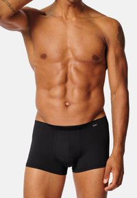 Svarta boxertrosor i mjukt tyg med en åtsittande design. Midjebandet är elastiskt och har en logotagg på sidan.