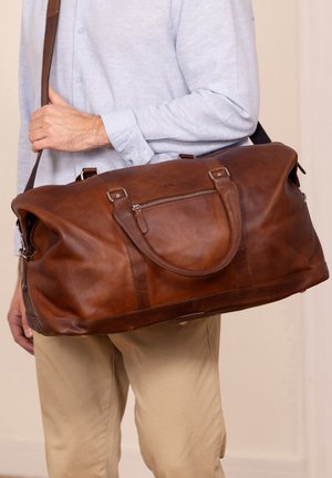 Bruine leren weekendtas met dubbele handgrepen, een afneembare schouderriem en een ritssluiting aan de voorkant. Soepele textuur, groot formaat.