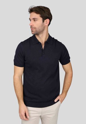 Polo shirt bleu marine foncé avec une texture douce, des manches courtes et un col classique. Comprend trois boutons et un ourlet côtelé pour un ajustement sur mesure.