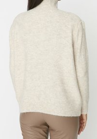 Cremefarbener Rollkragenpullover aus weichem Strickmaterial, mit gerippten Bündchen und Saum, lockerer Passform und glatter Textur.