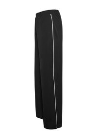 Pantalons larges noirs en tissu doux, avec une bande latérale blanche. La taille est élastiquée pour un confort optimal.