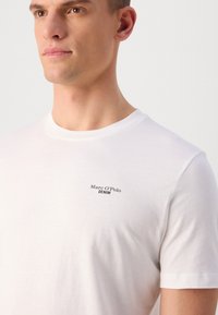 Witte korte mouwen t-shirt van katoen met een ronde hals. Heeft een klein zwart "Marc O'Polo DENIM" logo op de borst.