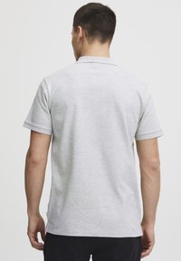Grå kortærmet poloshirt lavet af blødt, struktureret stof med en nedslået krave og synlig søm. Klassisk pasform med subtile sideaccenter.