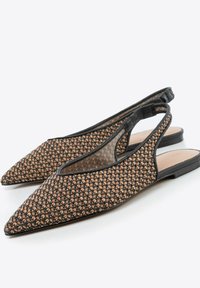 Sandały typu slingback z wąskim noskiem, wykonane z plecionego brązowego i czarnego materiału, z otwartymi bokami i płaską czarną podeszwą. Charakteryzują się minimalistycznym designem.