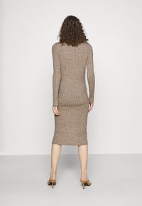 Ribbad midiklänning i taupe, som har långa ärmar och en figursydd silhuett. Texturen verkar mjuk, med en rundad fåll vid vaden.